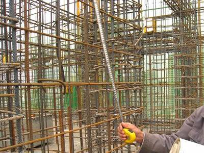 A worker is checking the spacing between reinforcing steel bars.